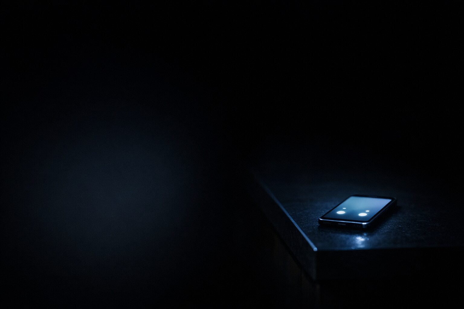 A small NZ workshop after dark with a desk phone showing 14 unread voicemails, the red voicemail light pulsing.